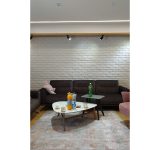 Модерна дневна соба со кафена софа и бел ѕид од декоративни тули / Modern living room with a brown sofa and white decorative brick wall.