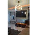 Луксузна ТВ зона со вграден електричен камин и стаклен лустер / Luxury TV zone with a built-in electric fireplace and glass chandelier.