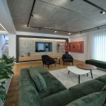 Луксузна дневна соба со темно зелена кадифена софа и индустриски бетонски плафон / Luxury living room with dark green velvet sofa and industrial concrete ceiling.