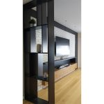 Модерна црна отворена полица која служи како преграда / Modern black open shelving unit serving as a room divider.