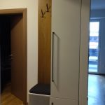 Modern wardrobe with integrated seating and a long black handle in the hallway