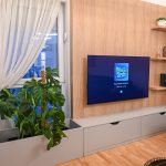 Модерна ТВ комода со вградени полици и декоративни растенија / Modern TV stand with built-in shelves and decorative plants.