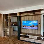 Голем ТВ систем со отворени полици интегриран во дрвена преграда / Large TV system with open shelves integrated into a wood partition.