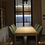 Модерна трпезариска маса со зелени тапацирани столици / Modern dining table with green upholstered chairs.