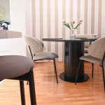 Модерна трпезарија со црна маса и тапети на вертикални линии / Modern dining room with a black table and striped wallpaper.