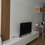 ТВ систем со вертикални дрвени летви и ниска бела комода / TV system with vertical wood slats and low white cabinet.