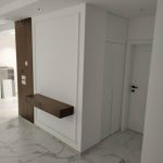 Modern entryway with a floating wooden shelf and large white closet